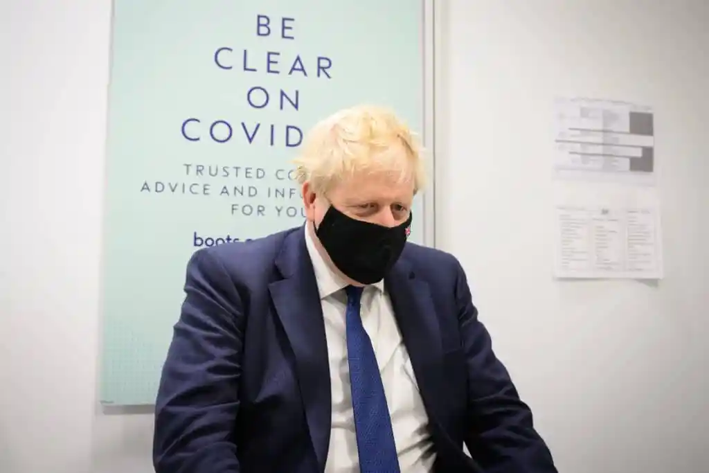 Boris Johnson prepares to watch a man receive his Covid-19 booster jab at a Boots pharmac