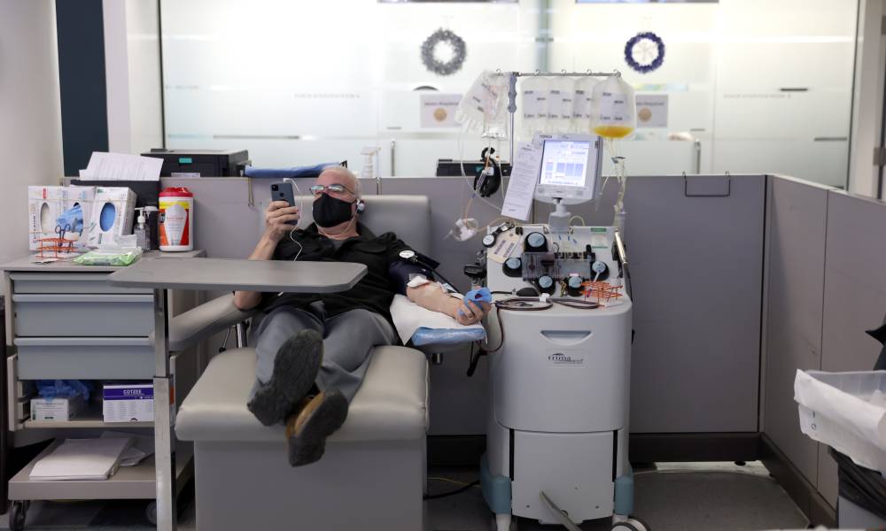 A man looks at his phone while donating blood at Vitalant blood donation center 
