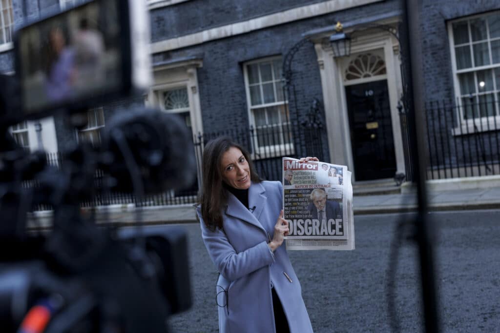 A journalist holds a copy of a newspaper outside 10 Downing Street
