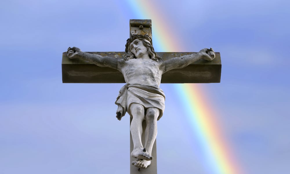 statue of Jesus in front of a rainbow