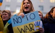 A person holds a sign that reads "No to war" that is in the colours of Ukraine's flag to protest Russia's invasion of the country