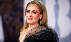Adele, a white woman, wears a black dress during an appearance at the 2022 BRIT Awards