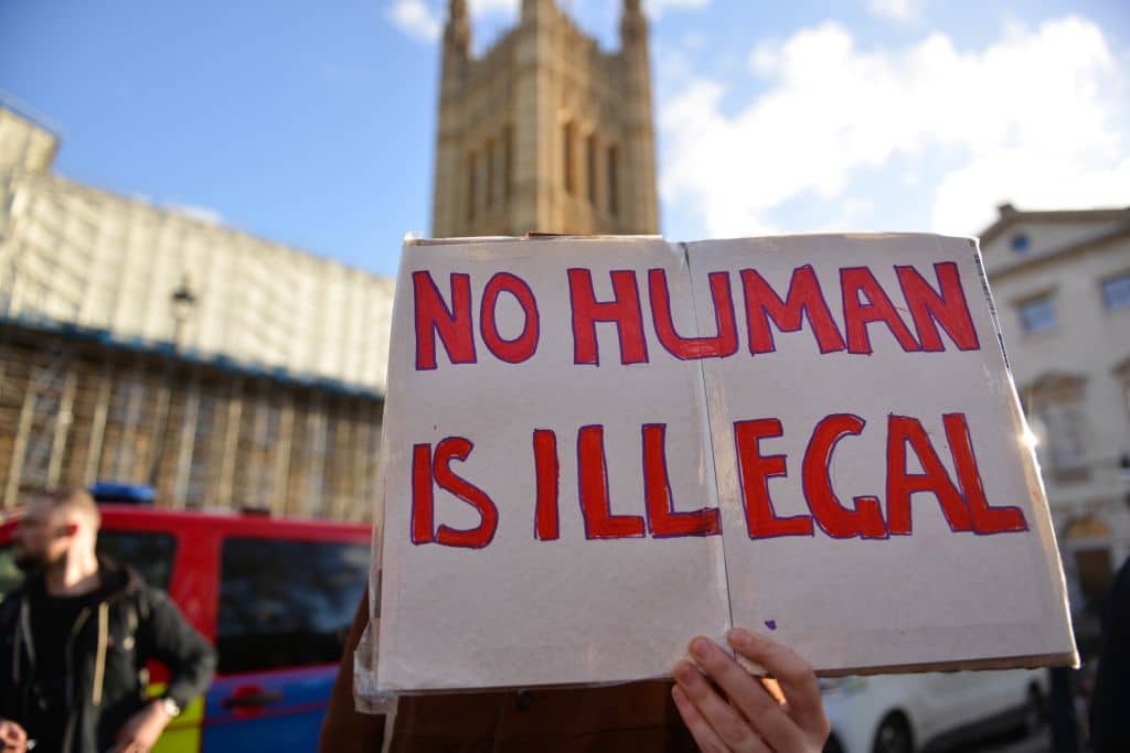 A protester holds a placard saying No Human Is Illegal