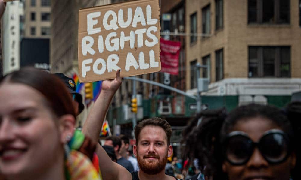 A participant is seen holding a sign reading "Equal rights for all" at a LGBT+ march