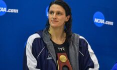 University of Pennsylvania swimmer Lia Thomas holds an NCAA trophy while she looks off to the side