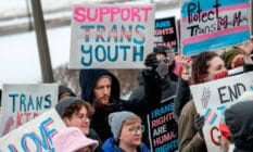 Person holds up a sign that reads "support trans youth" amid a rally in support of trans kids across the USA