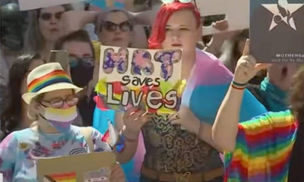 A person holds a sign up in support of the trans community that reads "HRT saves lives" amid protests in Texas