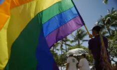 A person holds an LGBT+ flag as they participate in a march celebrating Honolulu Pride Month in Hawaii