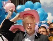 Boris Johnson wearing a pink stetson in front of blue, pink and white balloons
