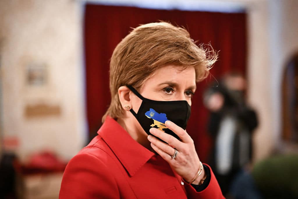 Scotland's first minister Nicola Sturgeon wearing a red jacket and a black face mask
