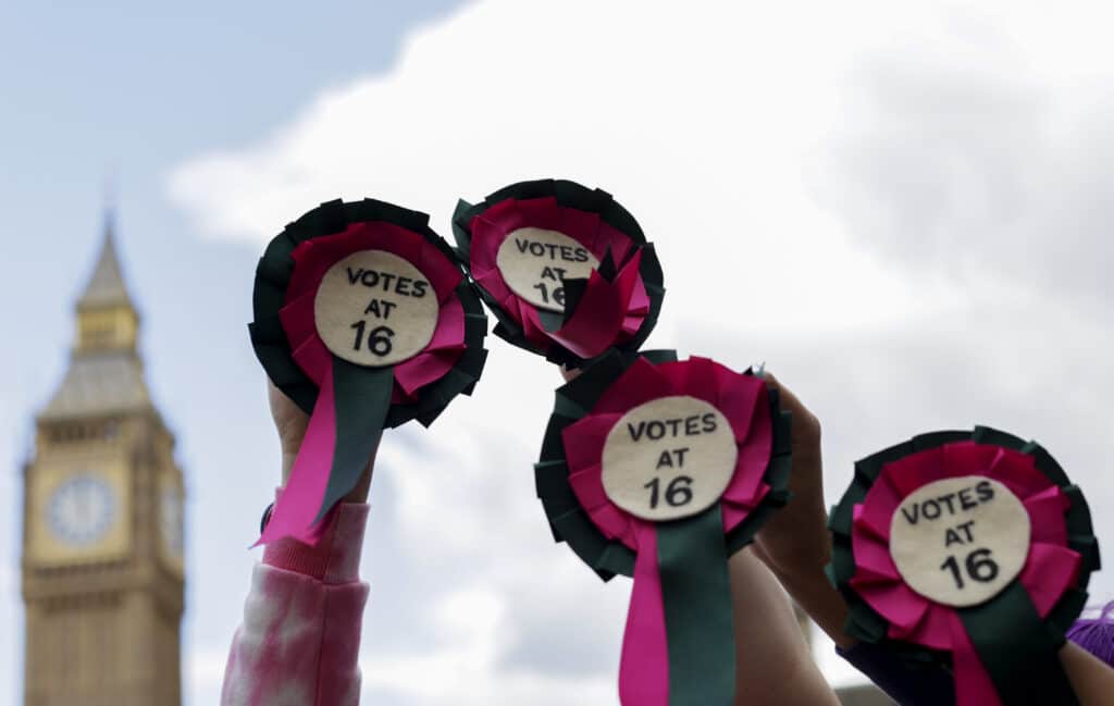 People hold up rosettes with 'votes at 16' on them