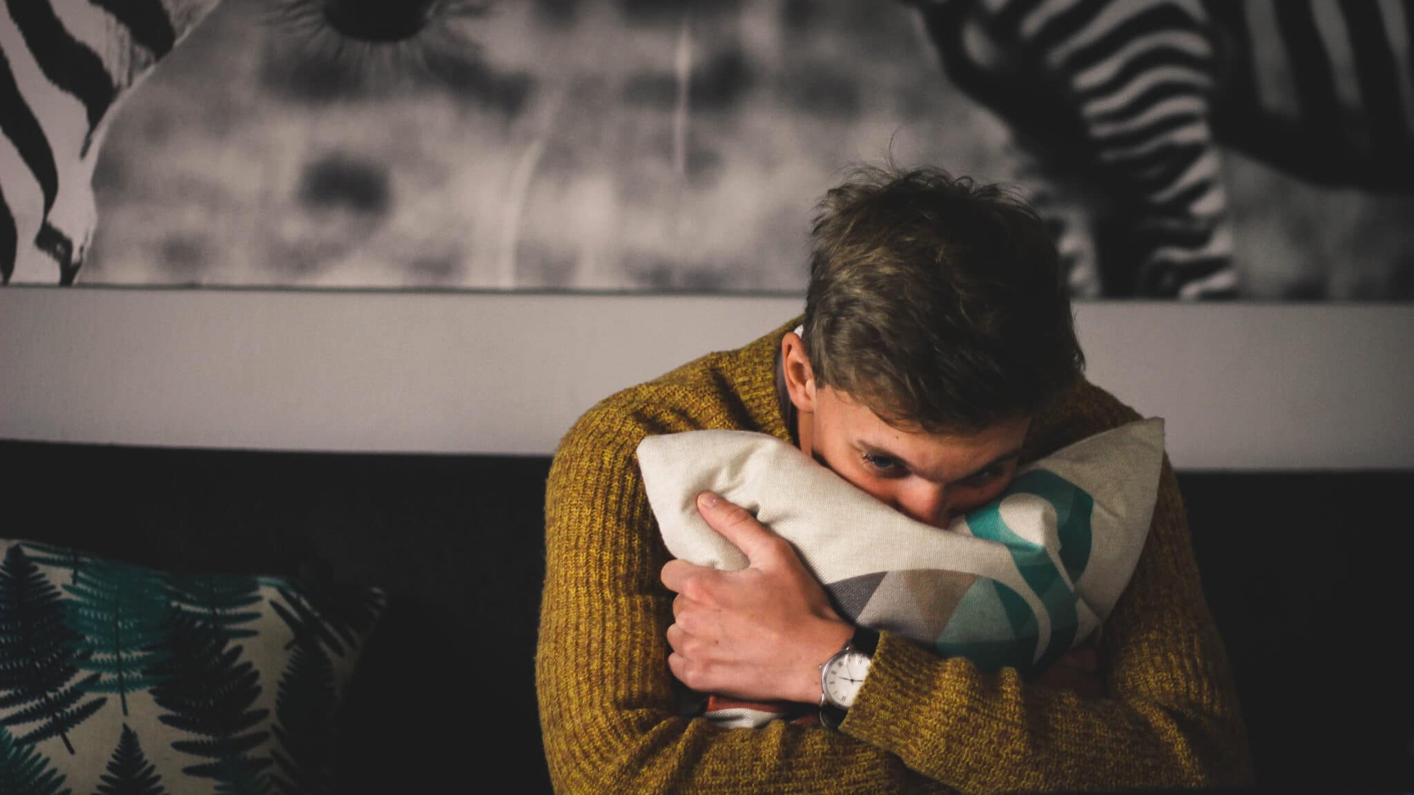 A man hugs a pillow in a bedroom
