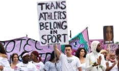 A person holds up a sign that reads "Trans athletes belong in sports" during a demonstration