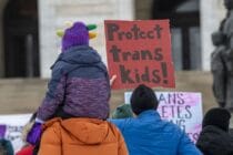 Protester holds a sign that reads 'protect trans kids'