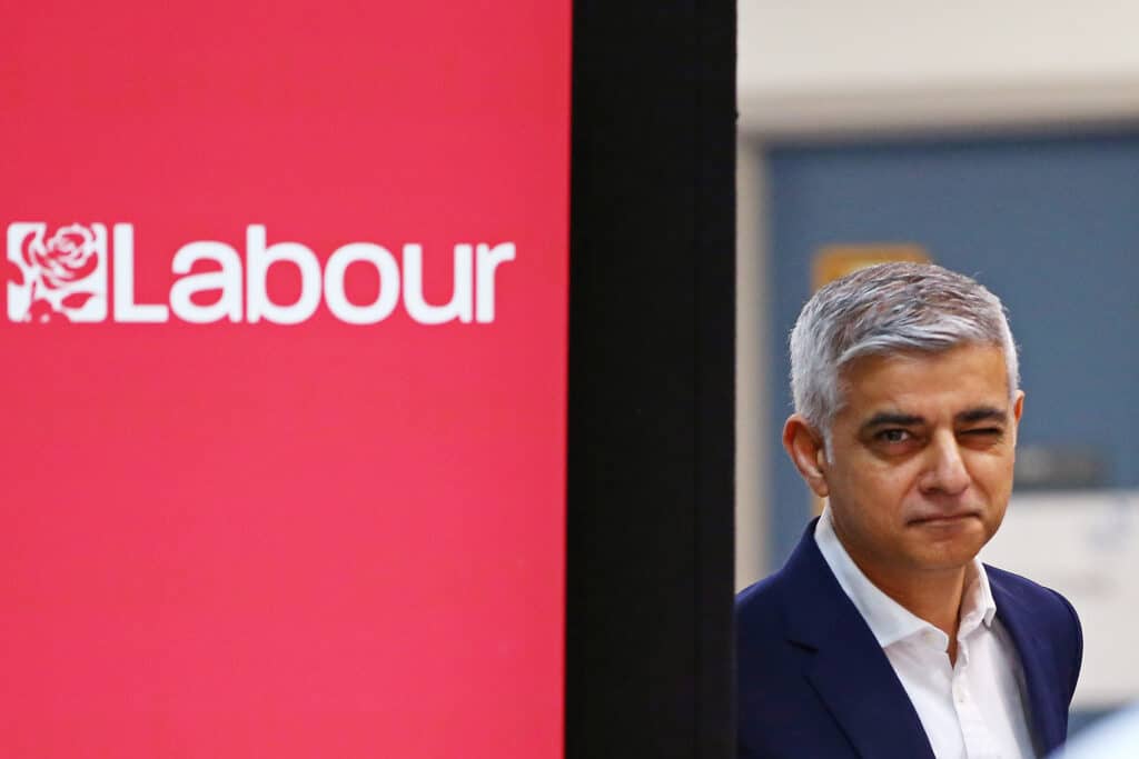 Sadiq Khan stands to a sign reading: 'London Labour'