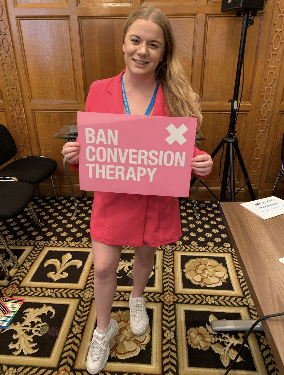 Elena Bunbury holding a sign that reads "Ban Conversion Therapy". 
