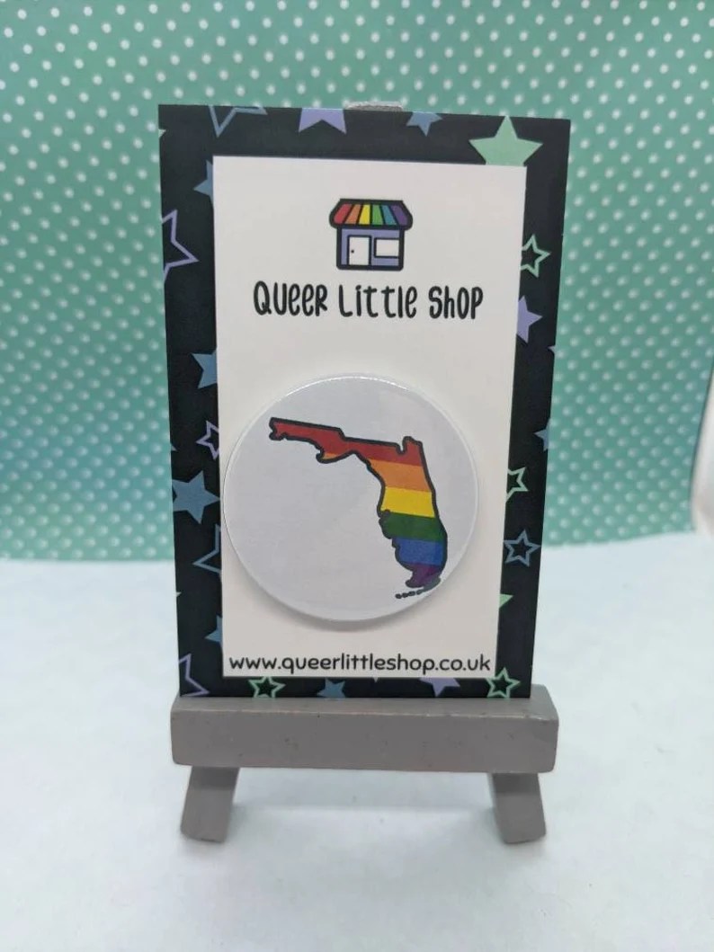 A rainbow pin in the shape of Florida. 