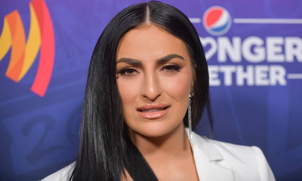 WWE superstar Sonya Deville stares at the camera while wearing a white jacket