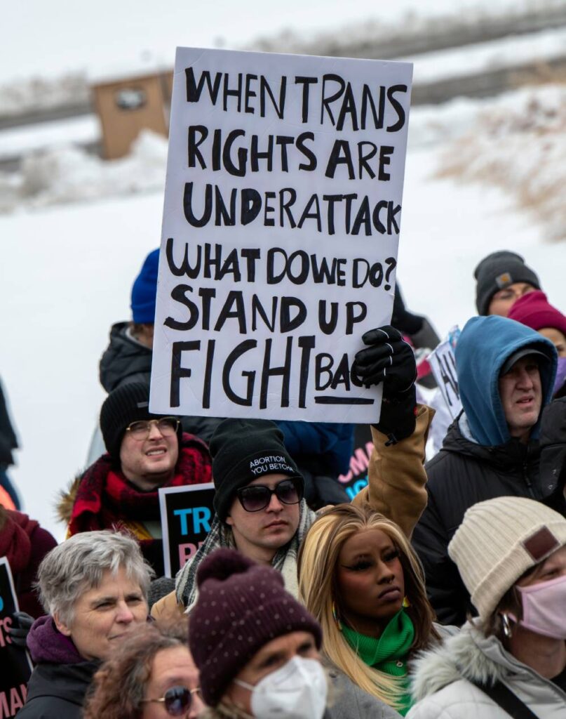 A person holds up a sign that reads 'when trans rights are under attack what do we do? stand up fight back'