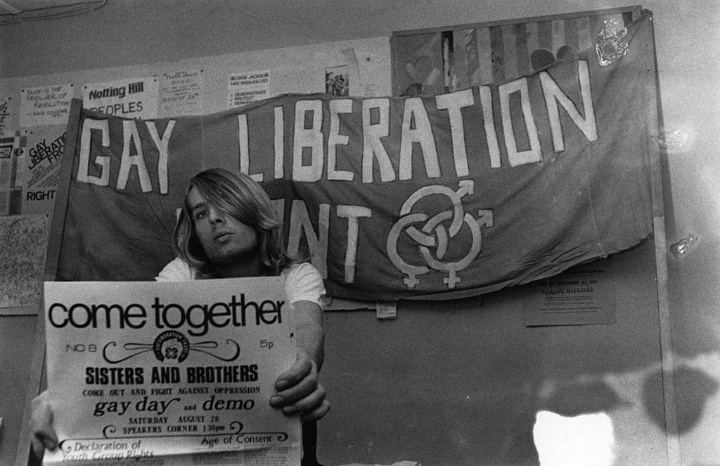 A member of the Gay Liberation Front holding a poster, circa 1971.