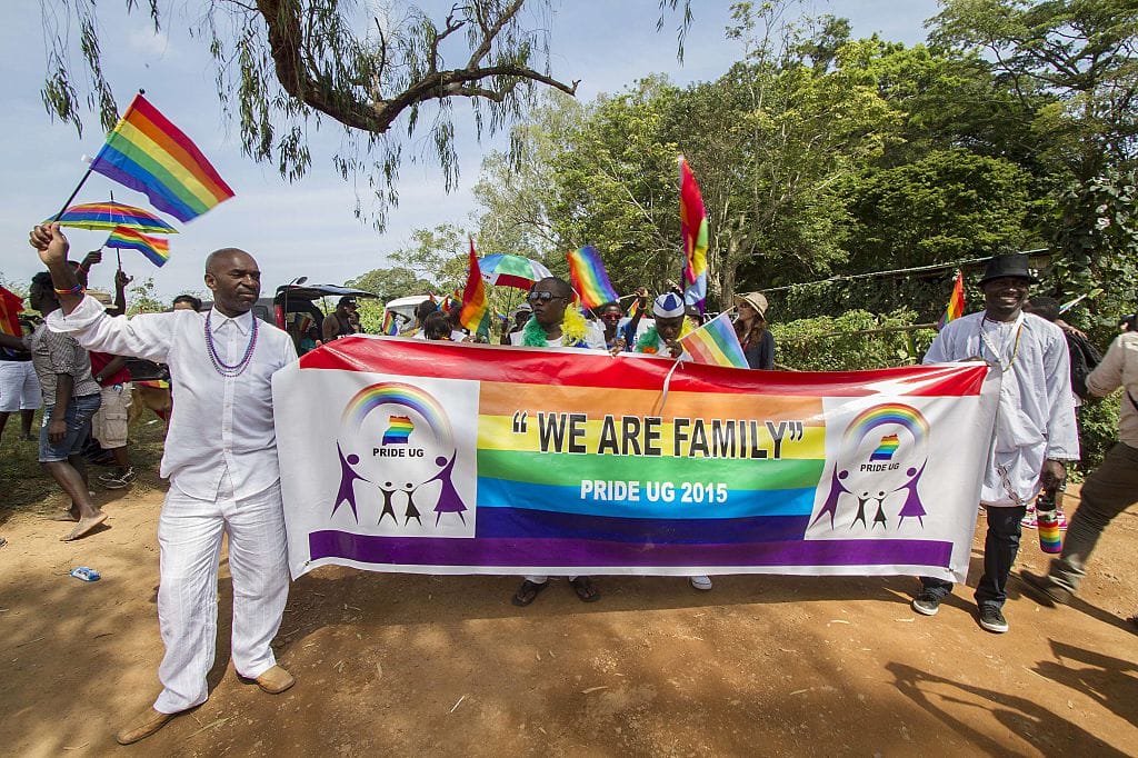 People hold a banner reading "We are Family" while waving rainbow flags as they take part in the Gay Pride parade in Entebbe on August 8, 2015.