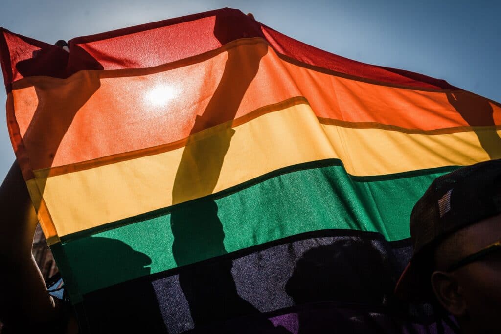 People hold up an LGBTQ+ Pride flag