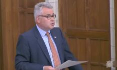 Tory MP Tim Loughton wears a blue shirt, orange tie and dark blue suit jacket during a parliament debate on non-binary legal recognition