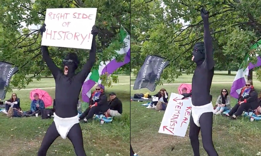 A man wearing an all-black morph suit with a sign reading, 'right side of history' and: 'real feminist'
