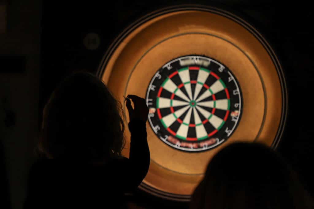 Silhouette of lady throwing darts at a dartboard