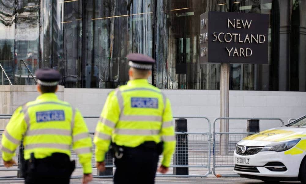 Two British police offices walk outside New Scotland Yard the home of the Metropolitan Police in London