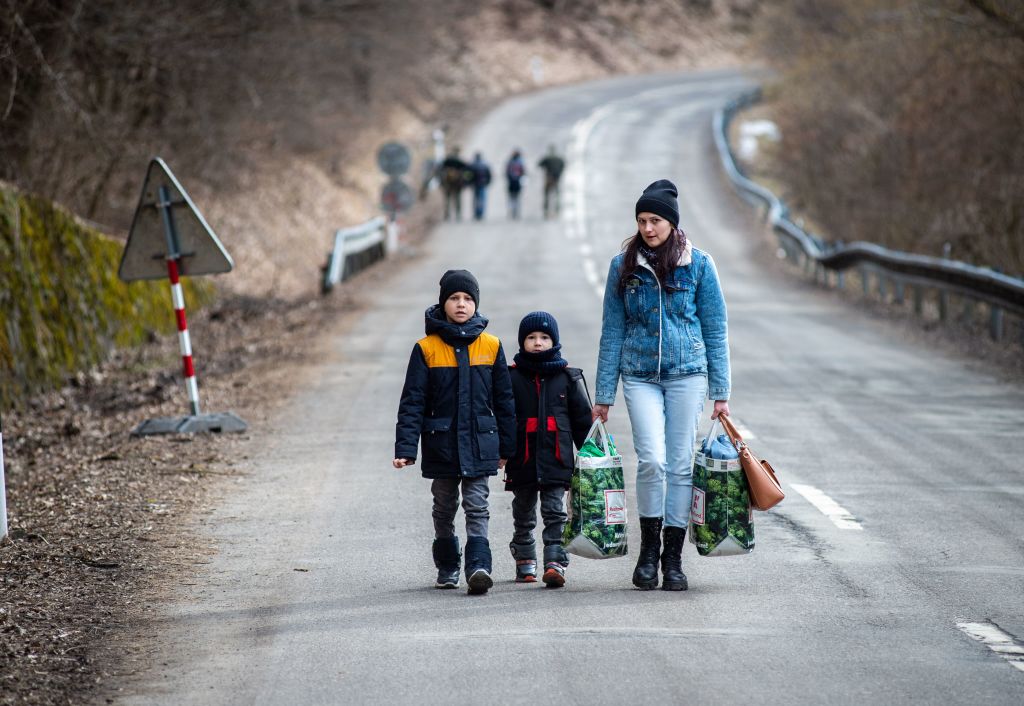 A woman with two children and carrying bags walk on a street to leave Ukraine after crossing the Slovak-Ukrainian border in Ubla, eastern Slovakia, close to the Ukrainian city of Welykyj Beresnyj, on February 25, 2022.