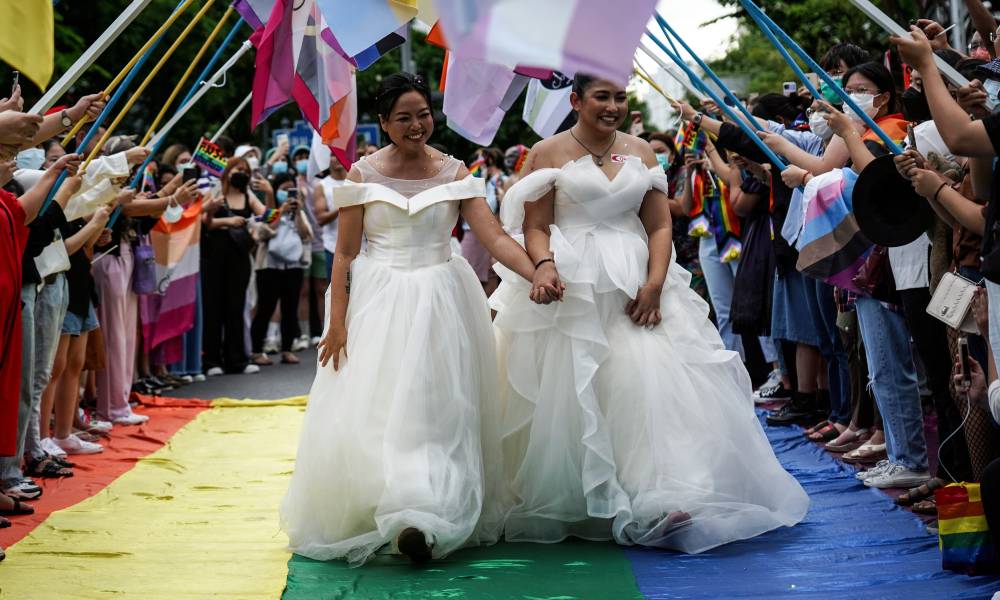 Members of the LGBTQ+ community are dressed in wedding dresses as they walk down a rainbow walkway while they take part in the parade to mark pride day 2022 in Bangkok, Thailand