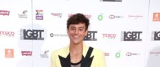 Tom Daley, dressed a pale yellow and black blazer, stands in front of the British LGBT Awards upon arrival