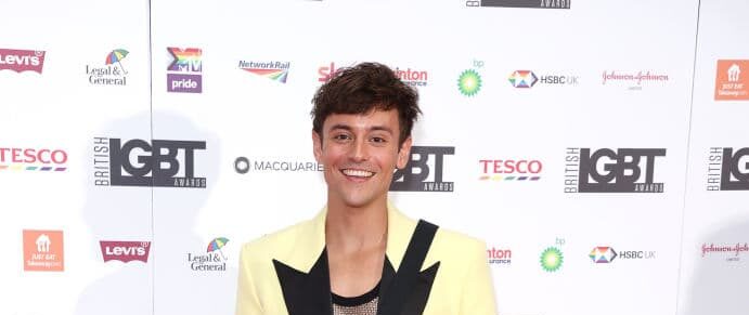 Tom Daley, dressed a pale yellow and black blazer, stands in front of the British LGBT Awards upon arrival