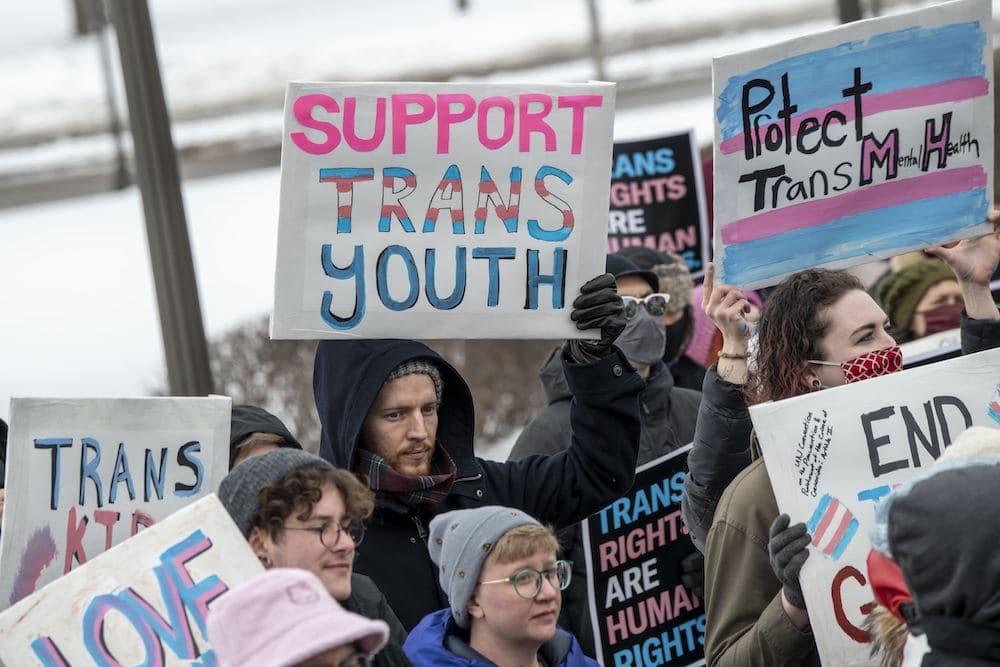 Families hold placards at a rally against increasing legislative attacks on trans kids across the US
