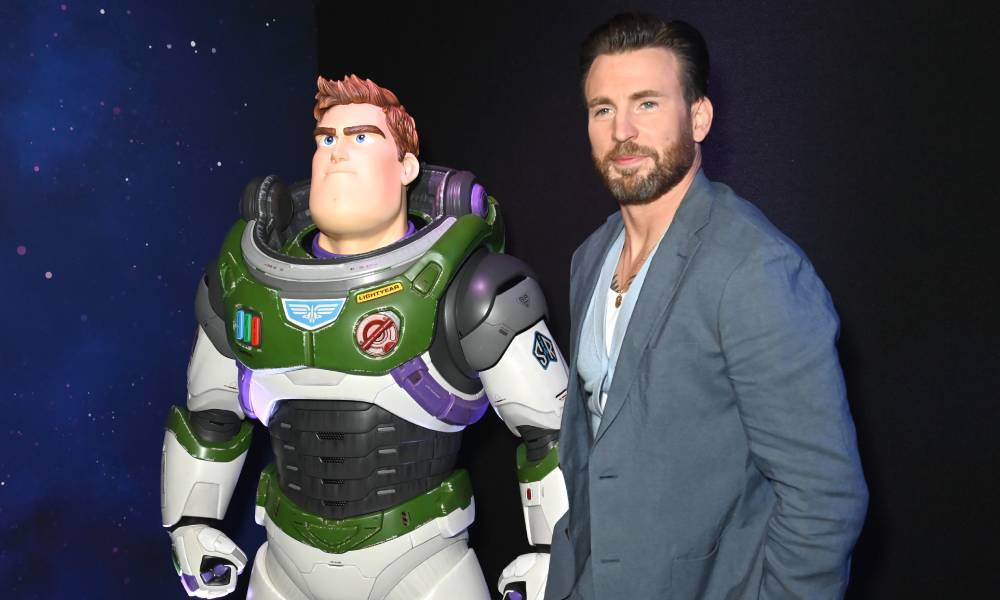Chris Evans wears a blue shirt and blue-grey blazer as he poses with a Buzz Lightyear character during the Lightyear UK Premiere at Cineworld Leicester Square 