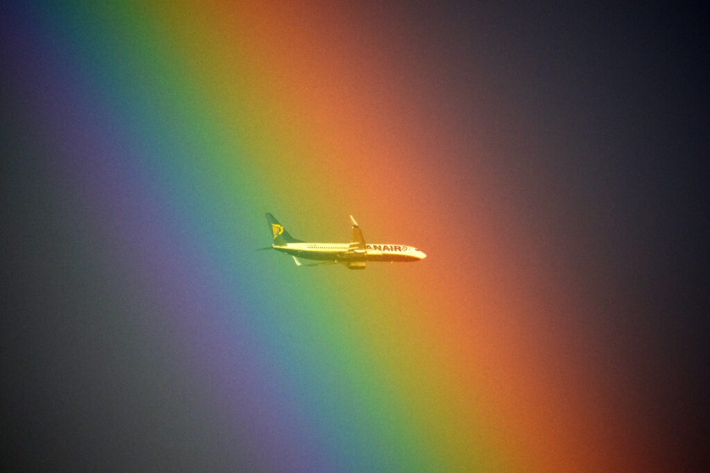 A plane of the Irish low cost company Ryanair flies in front of a rainbow