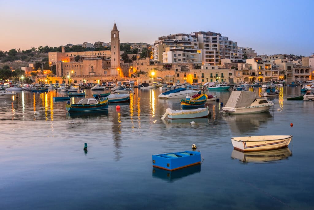 Fisherman and passenger boats in Marsaskala bay in Malta early in the evening