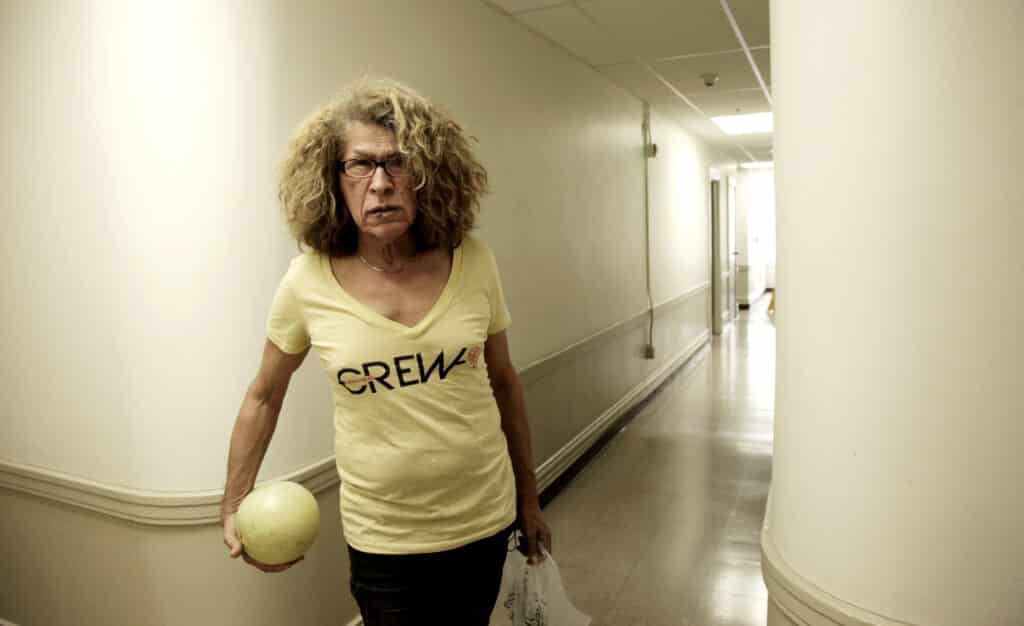 Donna in a corridor wearing a white top and holding a ball