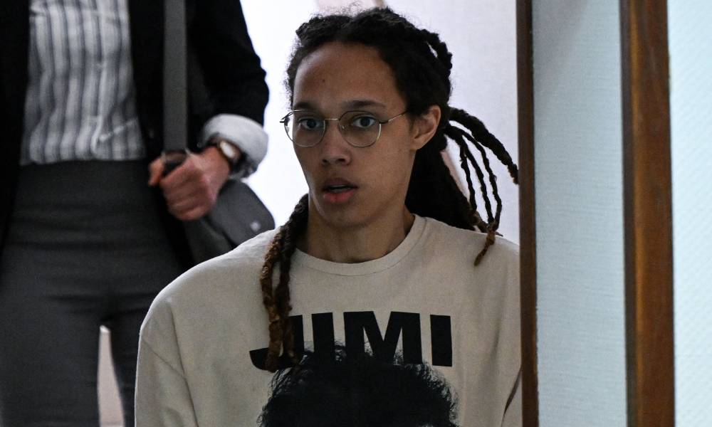 Brittney Griner wears a white t-shirt with black letter as she walks down the stairs in handcuffs to a trial hearing in Russia