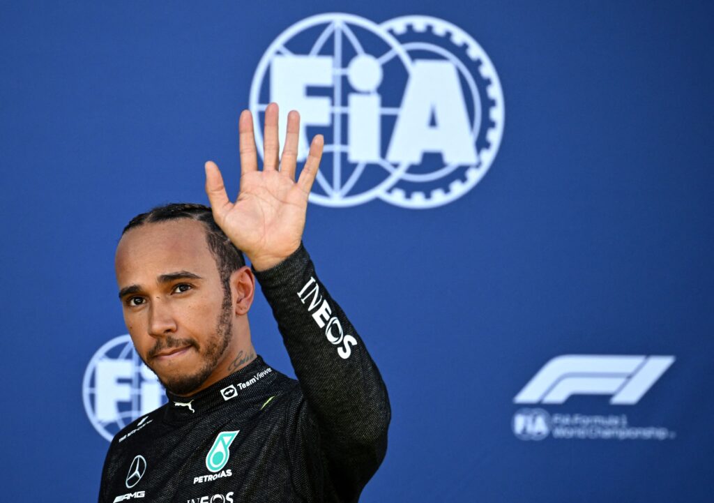 Lewis Hamilton waves as he walks back to the pits