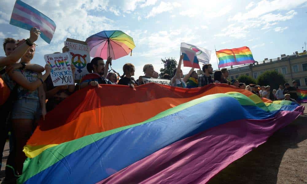 Activists wave rainbow flags during the gay pride rally in Saint Petersburg, Russia. The poeple hold up signs protesting against 'gay propaganda' laws and demanding change for the LGBTQ+ community