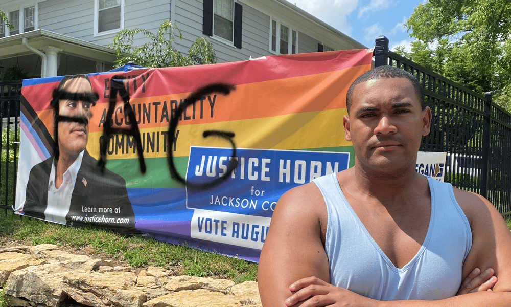 Justice Horn stands in front of his defaced banner