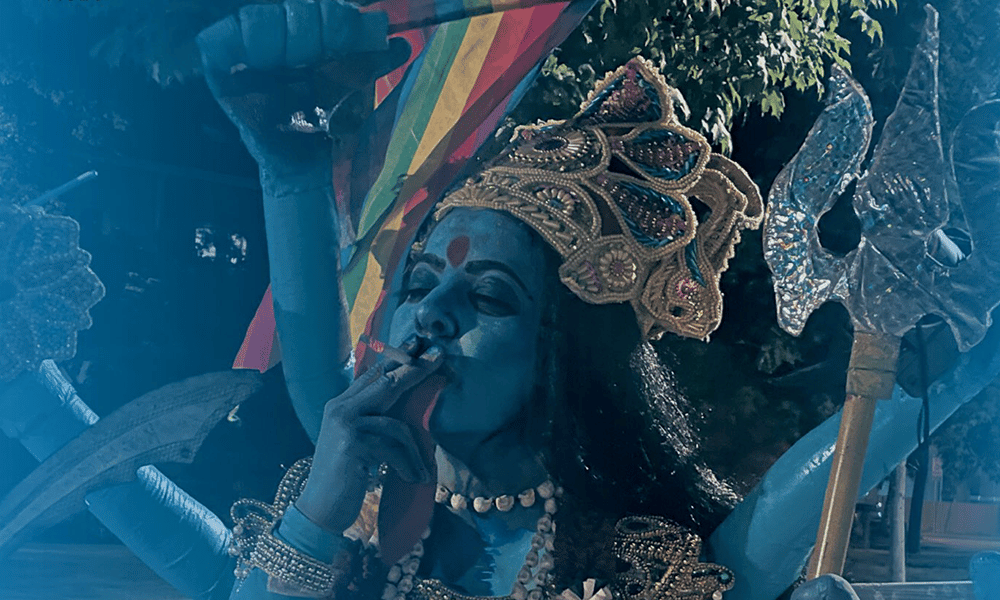 The poster for the upcoming documentary film Kaali, depicting a woman dressed as the goddess smoking a cigarette and holding a Pride flag