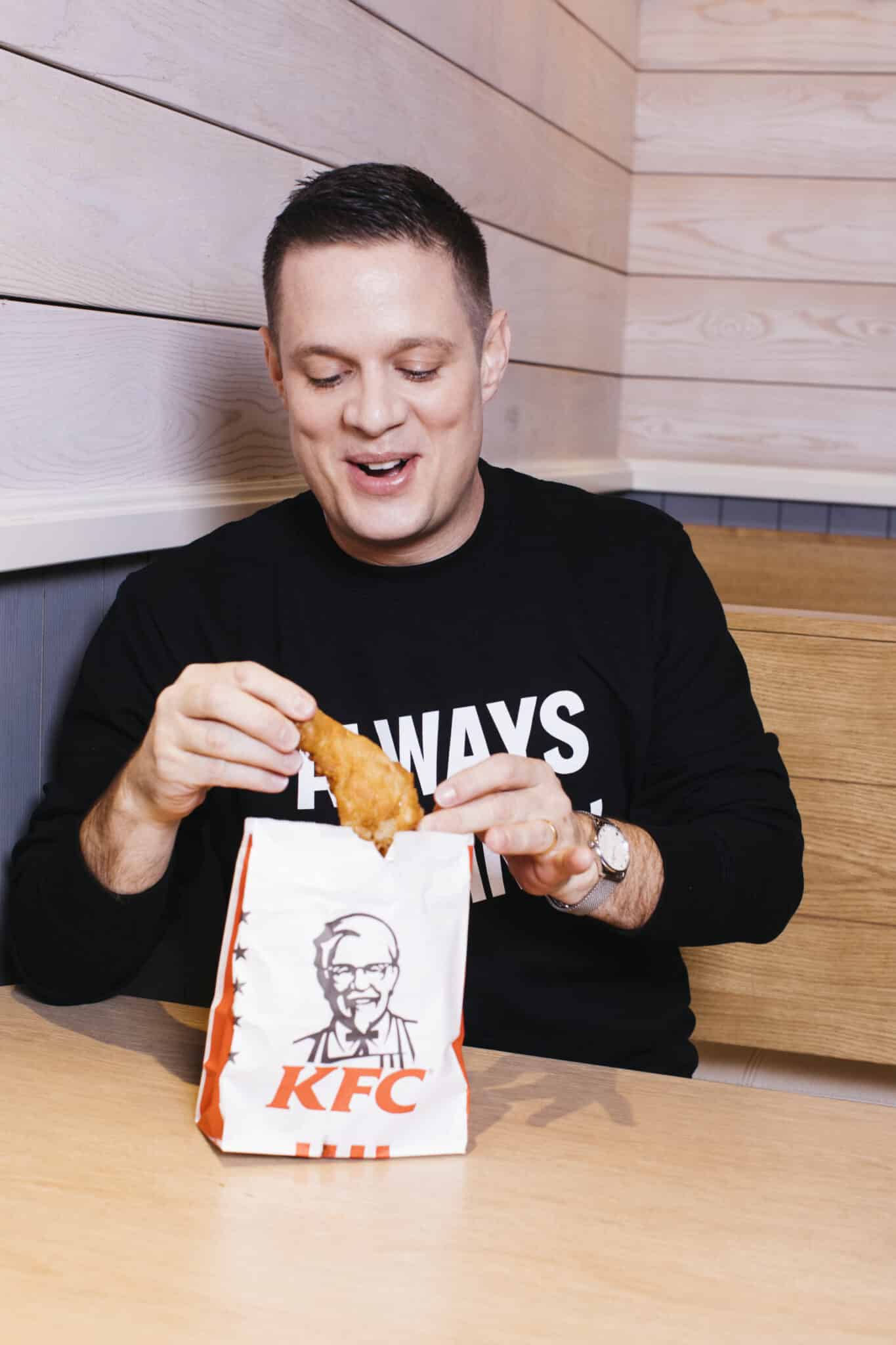 KFC boss Neil Piper pictured eating fried chicken from a KFC bag.