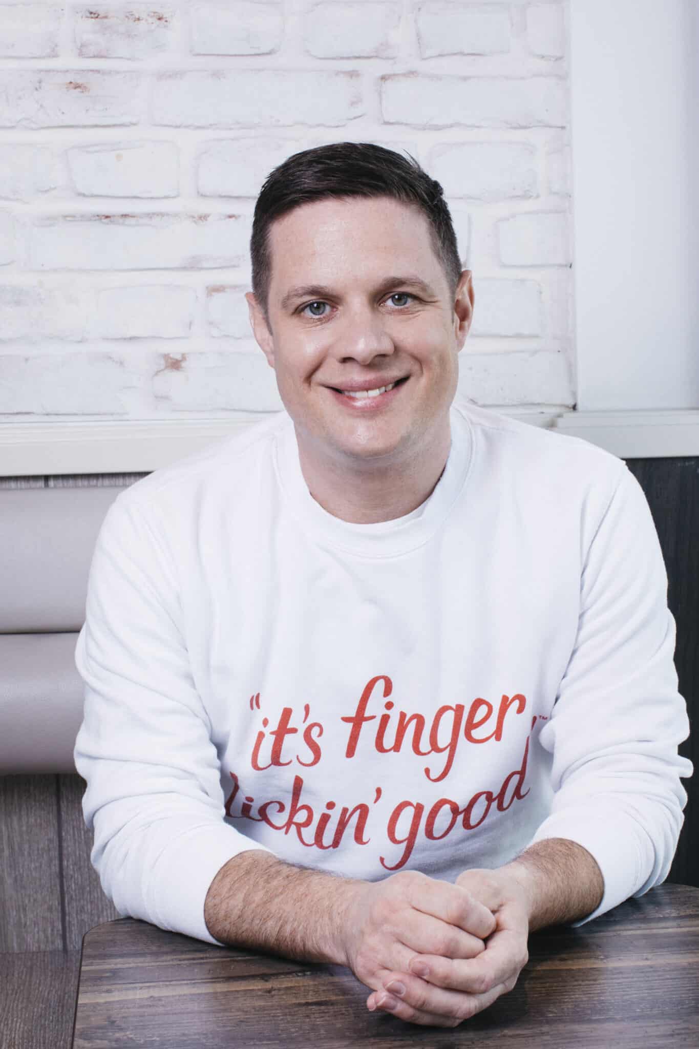 KFC's Neil Piper pictured wearing a sweater with the slogan "It's finger licking good". 