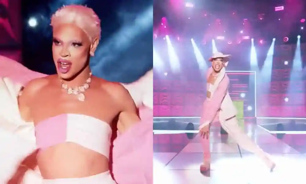 A black person with a pink wig and a pink and white outfit on a stage. 
