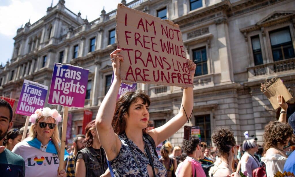 A person holds up a sign reading 'I am not free while trans lives are unfree' during a protest