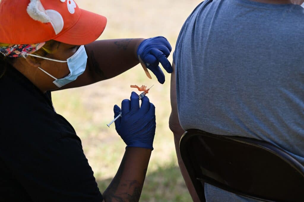 A public health worker wearing a face mask and surgical gloves administers the monkeypox vaccine at the Balboa Sports Center in the Encino neighborhood of Los Angeles, California, on July 27, 2022.