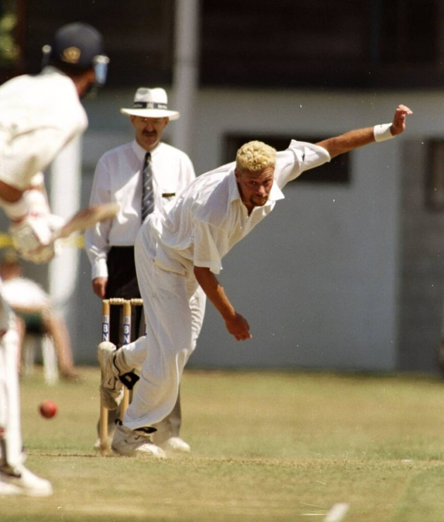 Heath Davis porte un uniforme de cricket blanc alors qu'il lance (ou lance) une balle de cricket